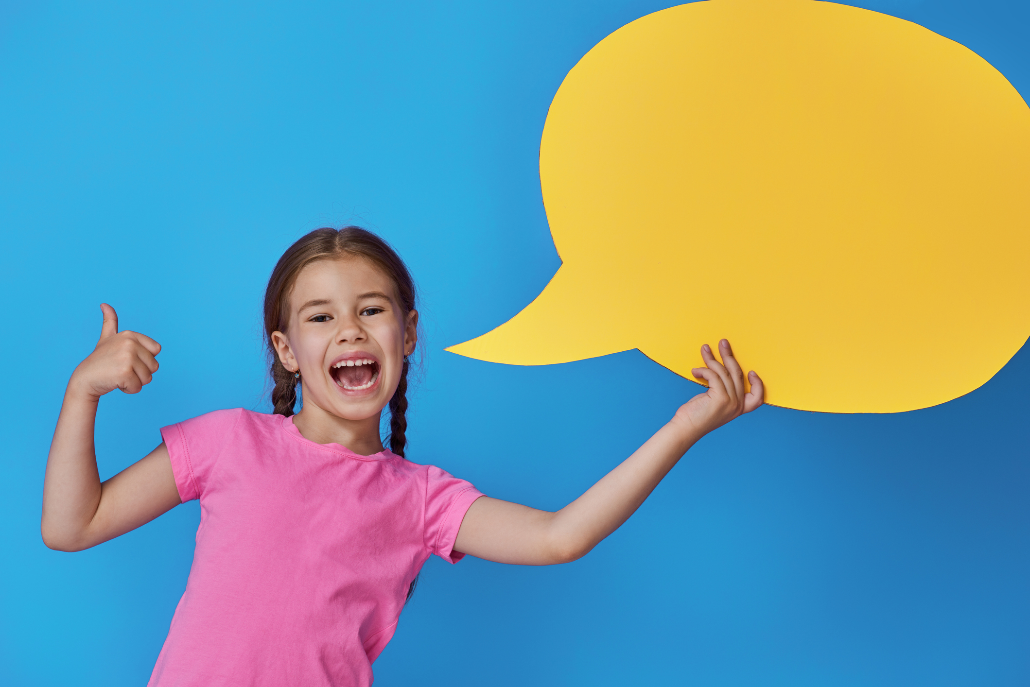 Cute little child girl with cartoon speech on colorful background. Yellow, pink and blue colors.